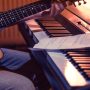 man playing acoustic guitar and piano close-up, recording notes